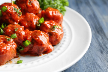 Plate with delicious meatballs on wooden table