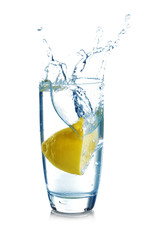 Falling sliced lemon into glass with water on white background