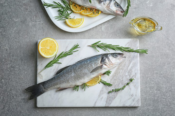 Fresh fish stuffed with rosemary and slice of lemon on marble board