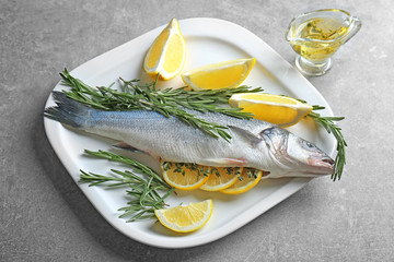 Fresh fish stuffed with rosemary and slices of lemon on table
