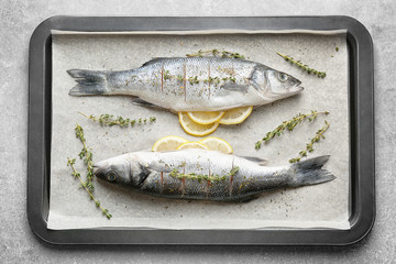 Fresh fish stuffed with slices of lemon on baking tray