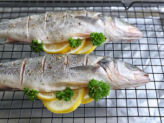 Fresh fish stuffed with slices of lemon on baking grid
