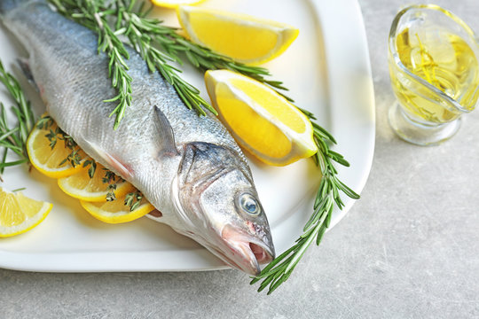 Fresh fish stuffed with rosemary and slices of lemon on table