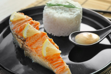 Plate with slice of salmon, rice and delicious sauce on table, closeup