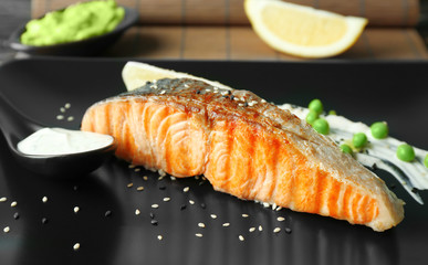 Plate with slice of salmon and delicious sauce on table, closeup