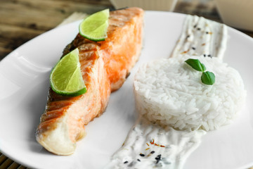 Plate with slice of salmon, rice and delicious sauce on table, closeup