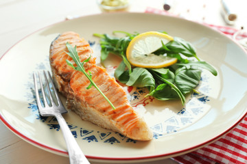 Plate with slice of salmon and herbs on table, closeup