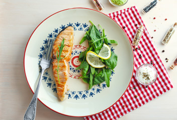 Plate with delicious salmon slice, herbs and small bowl of sauce on table