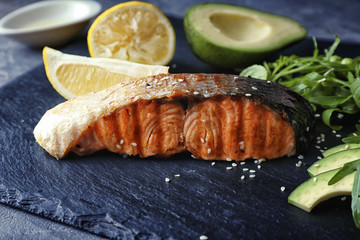 Slate plate with slice of salmon and ingredients on table, closeup