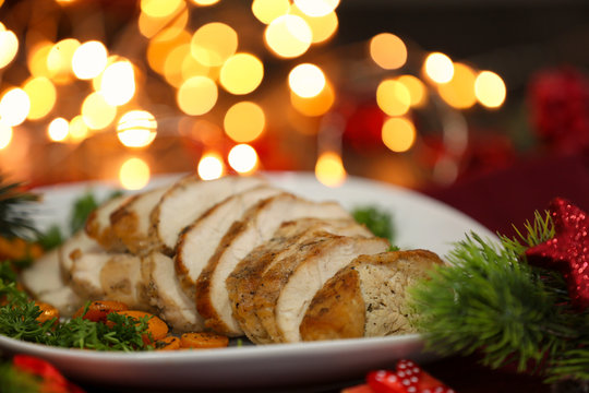 Plate with delicious sliced turkey breast against blurred lights
