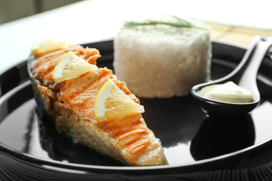 Plate with slice of salmon, rice and delicious sauce on table, closeup