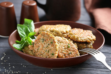 Delicious broccoli pancakes served with fresh basil leaves on brown plate in kitchen