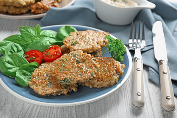 Delicious broccoli pancakes served with cherry tomato and basil leaves on kitchen table