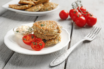 Delicious broccoli pancakes with sauce and cherry tomatoes on kitchen table