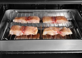Raw slices of fish fillet on roasting pan in oven