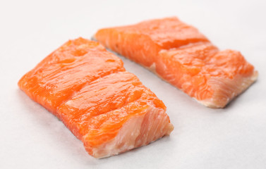 Two slices of red fish fillet on white paper, closeup