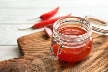 Composition with chili sauce in jar on table