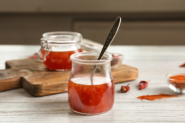 Composition with chili sauce in jars on table