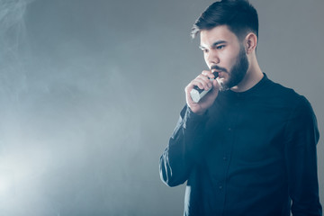 man with beard vaping an electronic cigarette. Vaper hipster smoke vaporizer