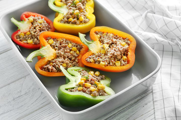 Quinoa stuffed peppers in baking dish on wooden background