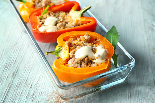 Quinoa stuffed peppers in baking dish on wooden background, closeup