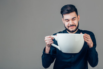 business man holding a funny huge and oversized cup of black coffee in caffeine