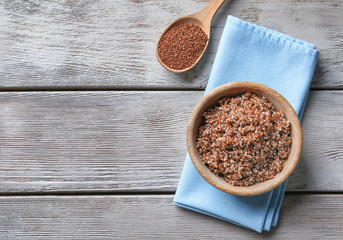 Bowl with boiled quinoa grains on wooden table