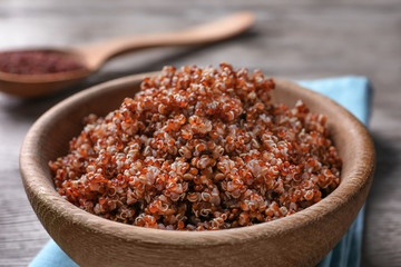 Bowl with boiled quinoa grains on wooden table