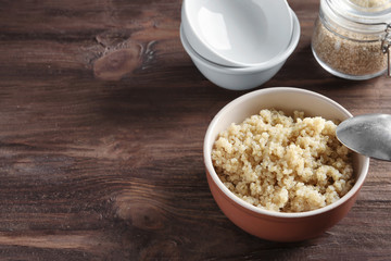 Bowl with boiled white quinoa grains on wooden table