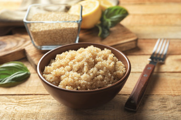 Bowl with boiled white quinoa grains on wooden table