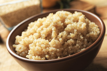 Bowl with boiled white quinoa grains on wooden table