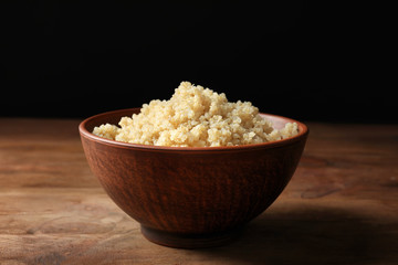 Bowl with boiled white quinoa grains on wooden table