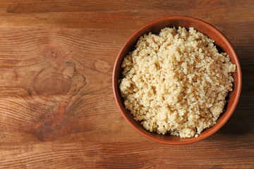 Bowl with boiled white quinoa grains on wooden table