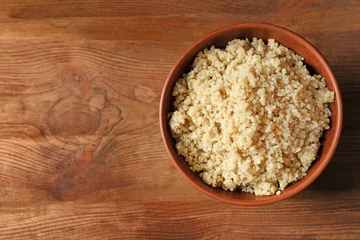 Zelfklevend Fotobehang Bowl with boiled white quinoa grains on wooden table © Africa Studio