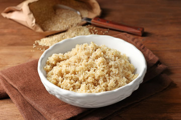 Bowl with boiled white quinoa grains on wooden table