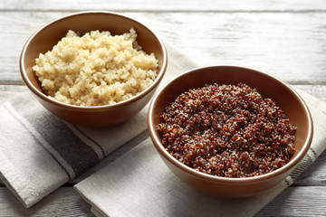 Bowls with boiled quinoa grains on wooden table