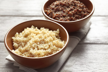 Bowls with boiled quinoa grains on wooden table