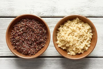Zelfklevend Fotobehang Bowls with boiled quinoa grains on wooden table © Africa Studio