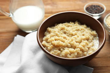 Bowl with boiled white quinoa grains on wooden table