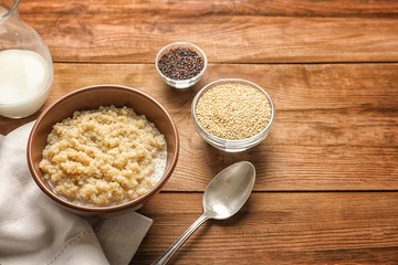 Bowl with boiled white quinoa grains on wooden table