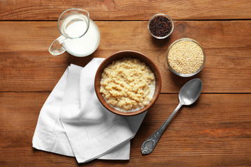Bowl with boiled white quinoa grains on wooden table