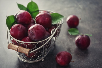 Fototapeta na wymiar Basket with fresh ripe plums on grey background