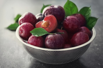 Naklejka na ściany i meble Sieve with fresh ripe plums on table