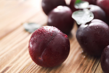 Fresh ripe plums on wooden table, closeup