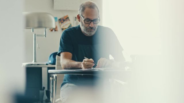 Narrow shot of a casual businessman working concentrated with his papers and documents on workdesk in modern office 