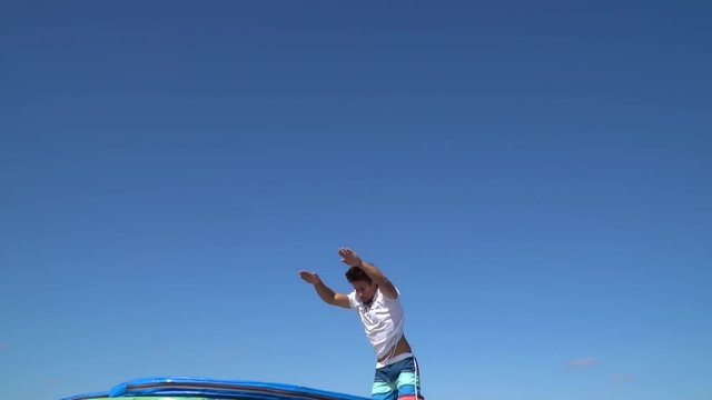 A brunette man is doing a somersault back in the air, slow motion
