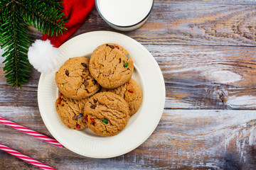Milk and cookies for Santa Claus and Santa's hat over wooden background. Xmas concept, greeting card. Toned image.