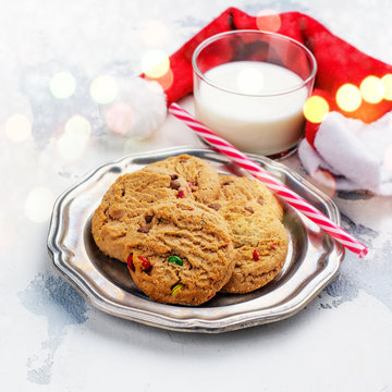Milk and cookies for Santa Claus and Santa's hat over wooden background. Xmas concept, greeting card. Toned image.