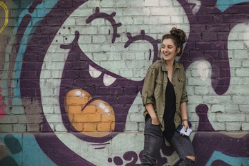 Beautiful casual girl near the wall with graffiti. Hipster girl. Life style.