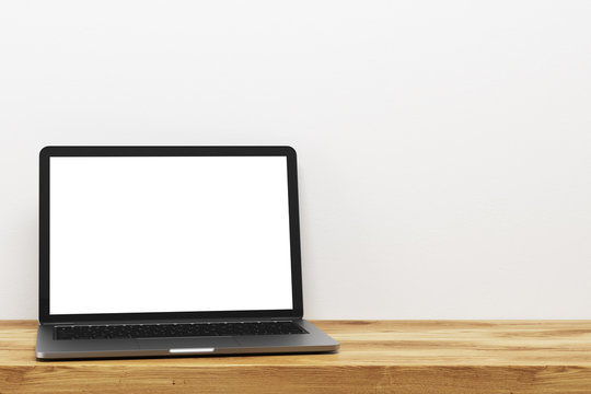 Laptop on a wooden table, white wall